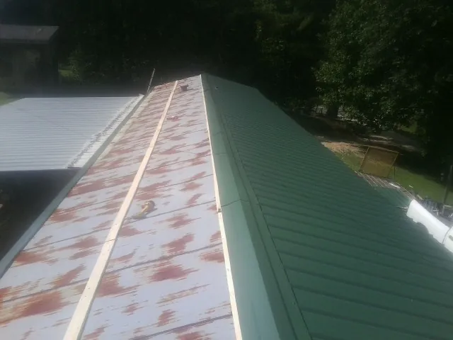 Old rusted panels beside newly installed green metal roofing — Wind Damage Roof Repair by Roofing Brothers in Lewisburg